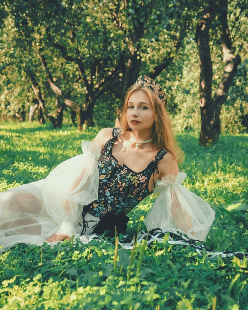 女性性とは何かを象徴するように、緑あふれる自然の中で優雅に座る女性のポートレート