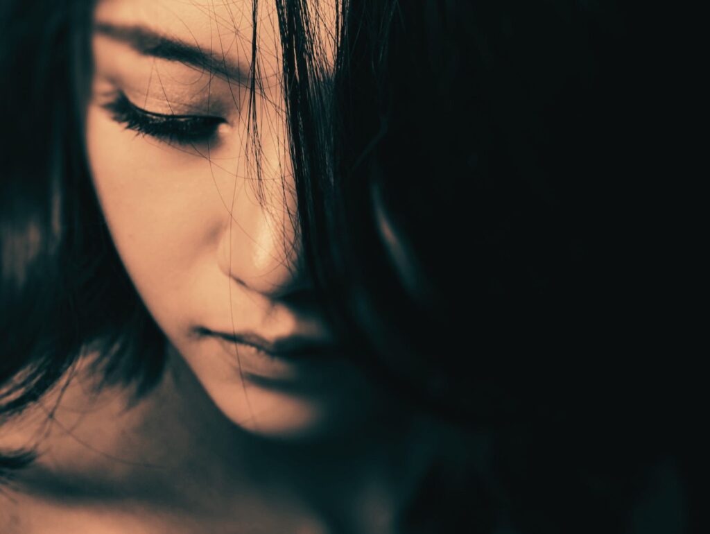 静かな光の中で目を閉じる女性。結婚や幸せについて内省し、自分の心と向き合う瞬間を表現した写真。