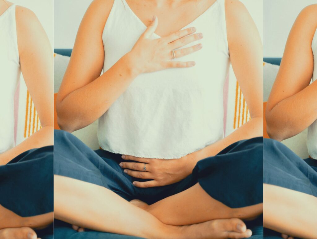 胸とお腹に手を当てて呼吸を感じる女性。フェムケアやセルフラブを通して心と身体をつなぐ瞑想的なセルフケア。
