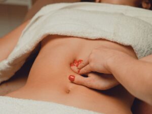 お腹を優しく押している腸もみやチネイザンの施術の様子。腸の働きを整え、身体と心をゆるめるケアのイメージ。