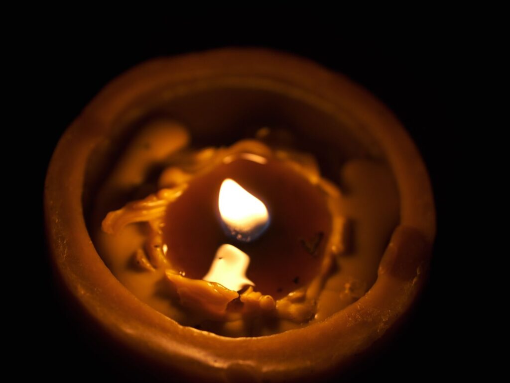 蜜蝋キャンドルの優しい炎が静かに揺らめく様子。自然素材のろうそくが放つ温かな光が、空間と心を穏やかに包み込む。