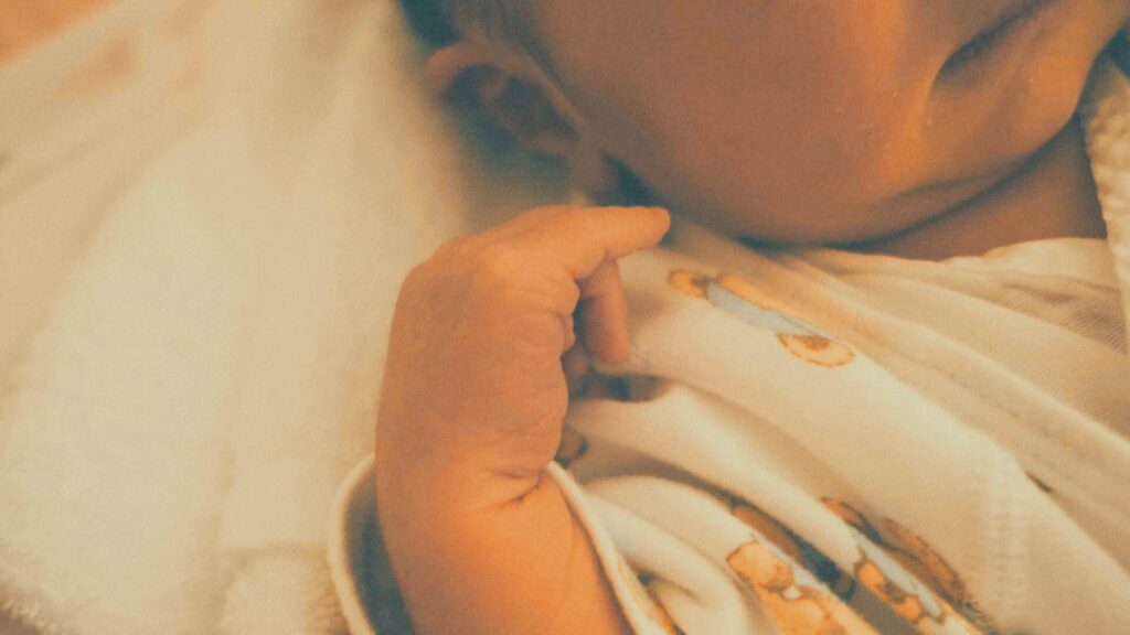 赤ちゃんの小さな手のクローズアップ写真。命の誕生と不妊の原因を考える文脈で、ストレスや睡眠不足、身体の状態が妊娠や子宮・精子の健康に与える影響を象徴的に表現している。