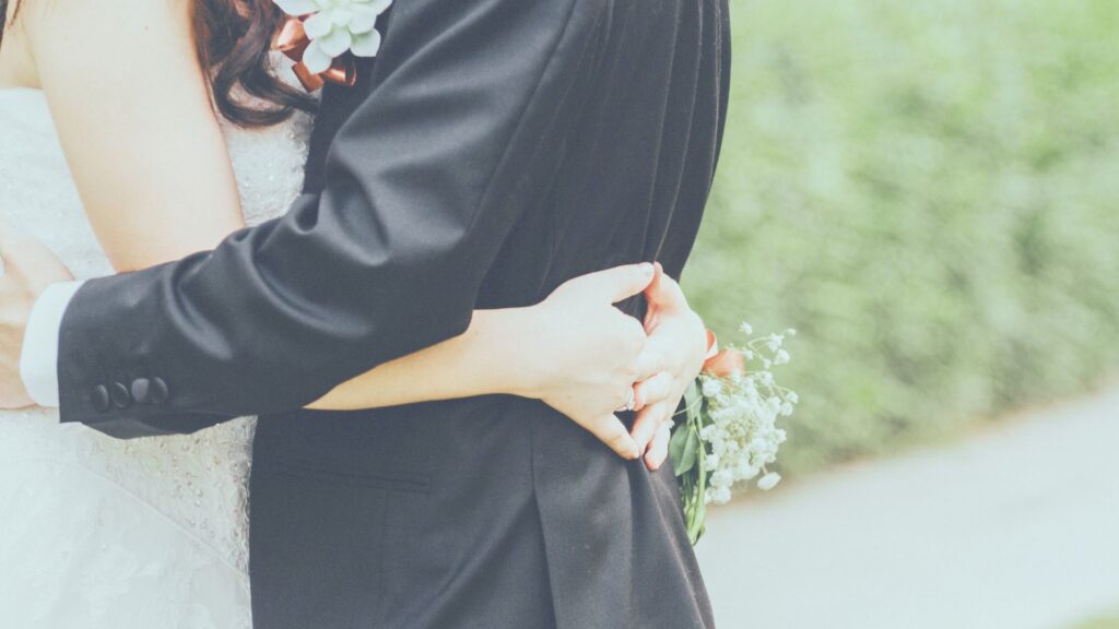 結婚式で寄り添う新郎新婦の後ろ姿。結婚や離婚を失敗と捉えず、パートナーシップを通して本当の自分に戻るプロセスを表現したイメージ写真。