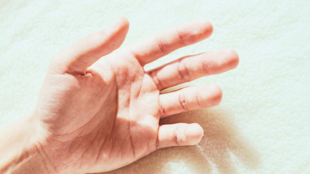 やさしい光の中で開かれた手のひら。触れることで触れられる感覚を象徴する、撫でるリンパドレナージュとタッチケアのイメージ