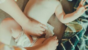 赤ちゃんのおむつ替えをする母親の手。子育てのリアルな日常と育児の負担を表すイメージ。