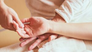 セラピストが手に触れて施術する様子｜心と身体を癒すセラピー・ボディケアのイメージ