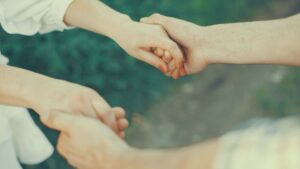屋外で男女が手を取り合う様子。安心感と信頼を象徴するやさしい触れ合いのイメージ。