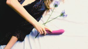 ヨニワンドを使ったセルフプレジャーのイメージ｜女性の手元と花を添えたフェムケア・リラクゼーションのビジュアル
